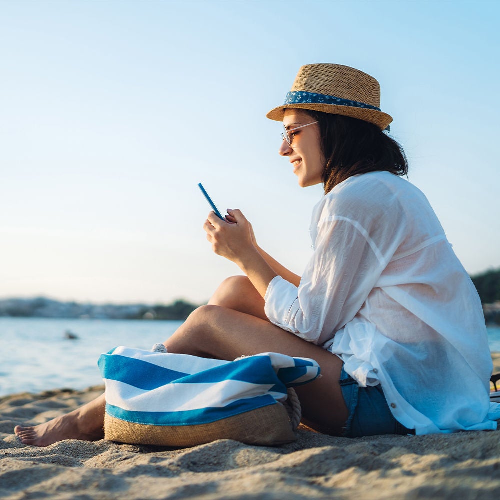 Woman on the beach, on her phone.